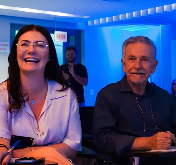 Dois colaboradores da Seprol sorrindo durante evento com iluminação azul